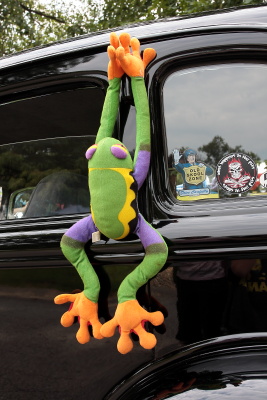 Long stuffed frog hanging from the door of a hot rod