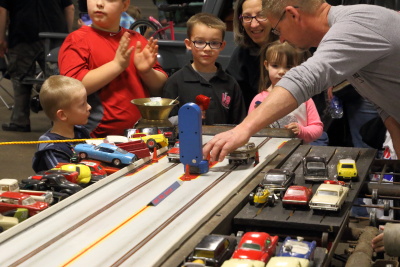The grandchildren doing the slot car racing with the help of Mike Lowhorn